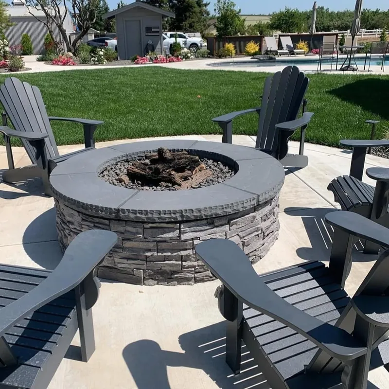 Stone fire pit ringed with chairs on a patio laid by R.S.G. Masonry
