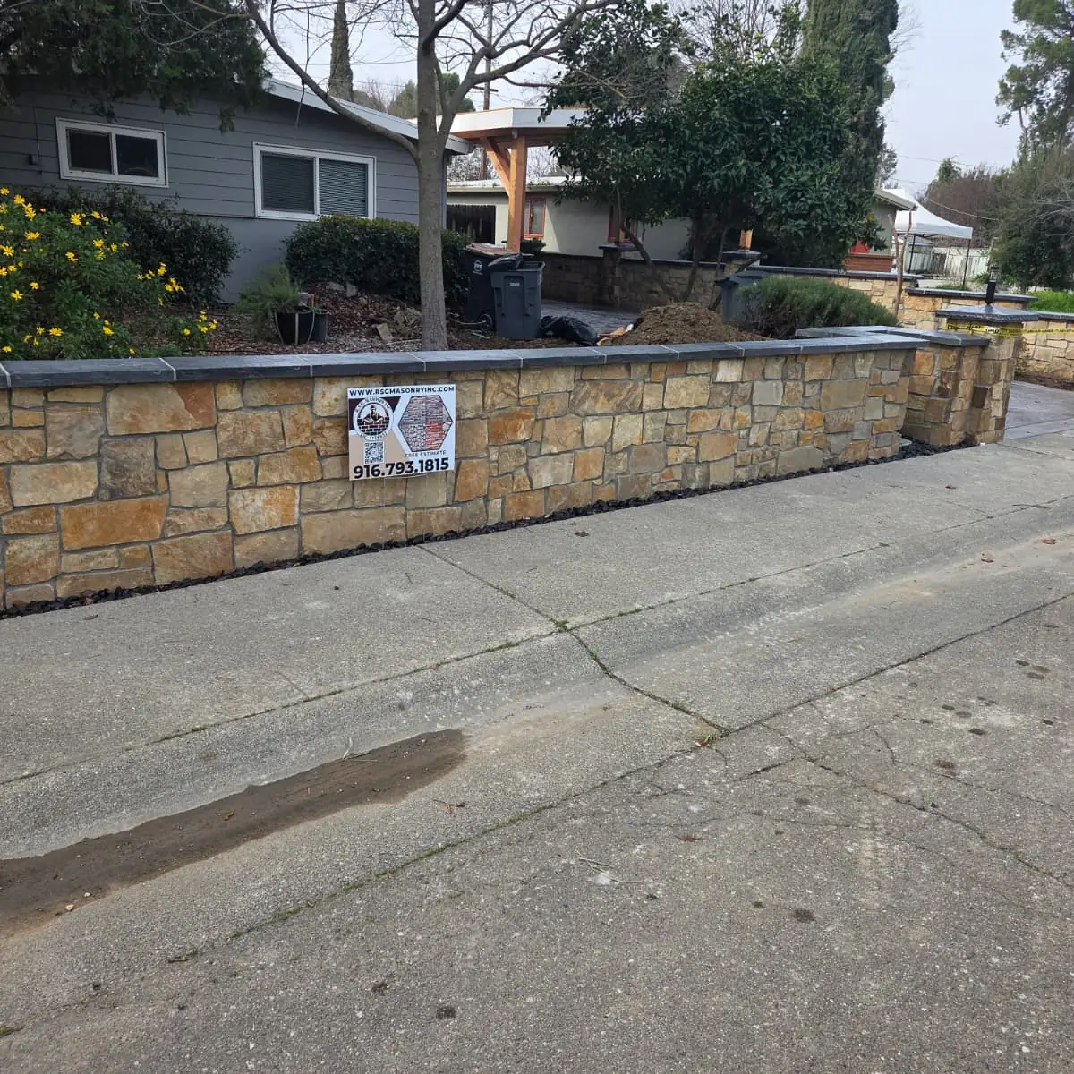 Long stone faced garden wall running beside a Sacramento driveway