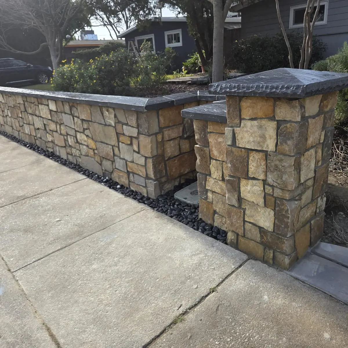 Stone garden wall and capped pillars along a Sacramento driveway